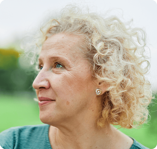 Vrouw met grijs krullend haar kijkt opzij